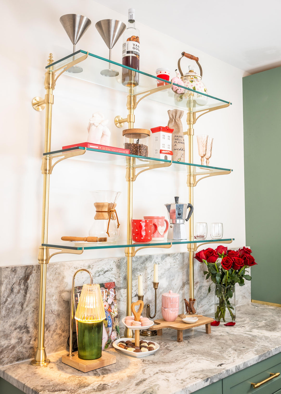 A customizable cantilever bistro shelving unit made from real brass with glass shelves that is mounted to the wall and countertop.